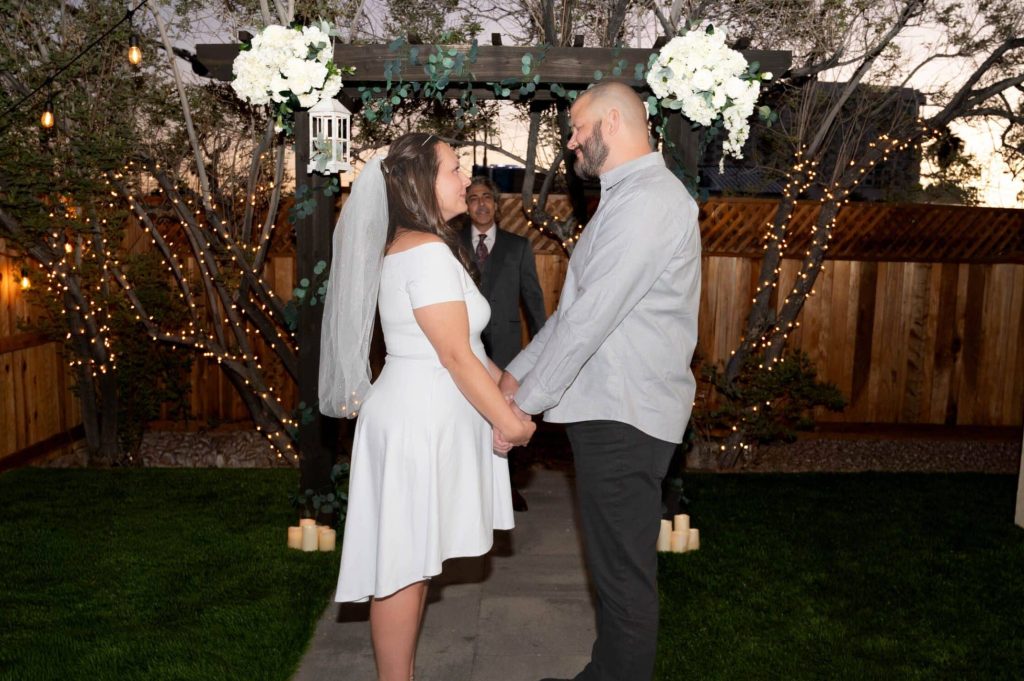 Bride and groom exchanging vows beneath glowing string lights at Mon Bel Ami Wedding Chapel’s gazebo.